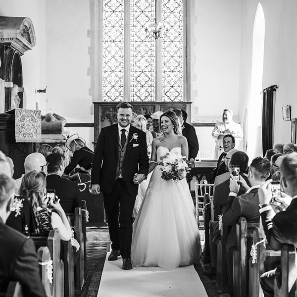 The happy newlyweds walk up aisle as husband and wife at this church wedding in Norfolk