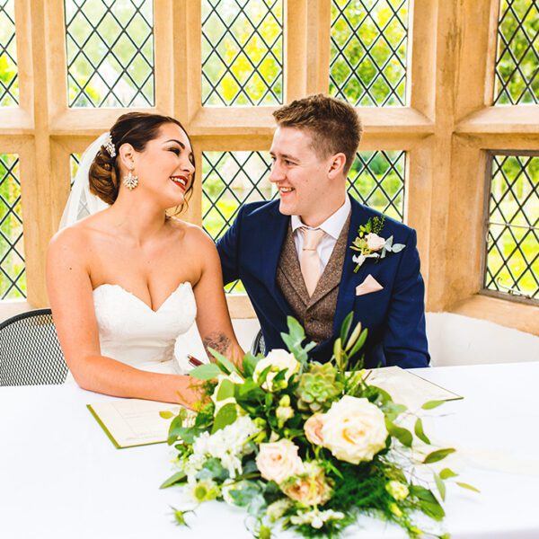 The happy couple sign the register following their wedding ceremony at Oxnead Hall